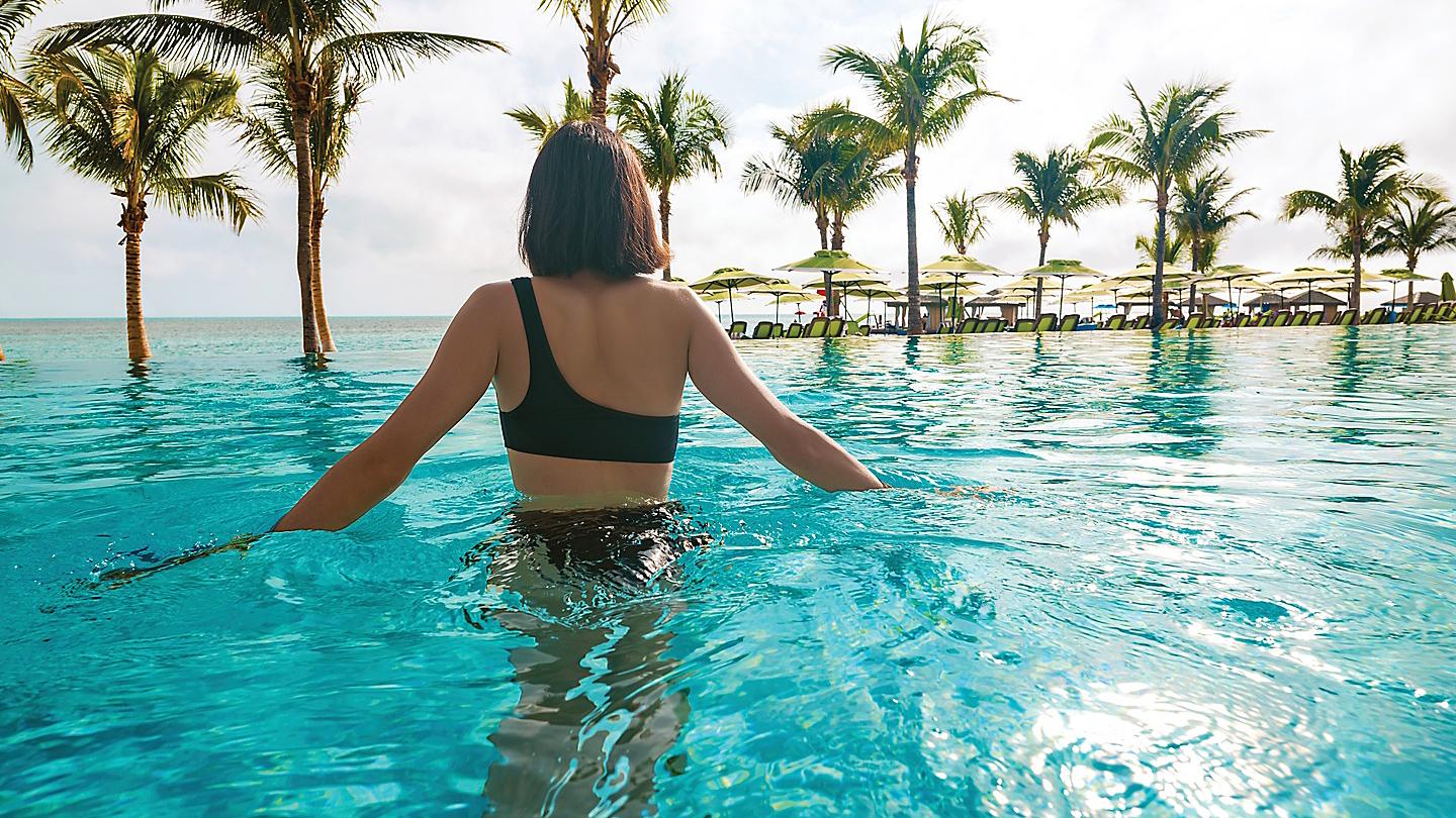 perfect-day-coco-beach-club-woman-splashing-infinity-pool-palm-trees