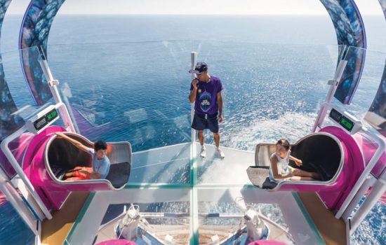HM, Harmony of the Seas, boy, girl, teens, smiling, looking at each other at start of race down Ultimate Abyss water slide, fun, action, ocean view in background, staff person in center